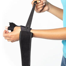 Load image into Gallery viewer, Person in the process of wrapping the wrist strap around their wrist. The thumb spica is on their left hand.
